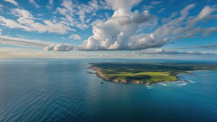 Obraz premium Breathtaking Aerial View Of Coastal Landscape With Lush Greenery Under A Blue Sky And Fluffy Clouds
