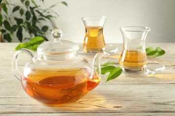 Freshly brewed tea in glass cups and teapot on wooden table