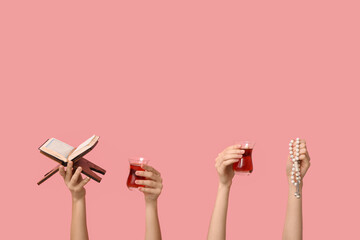 Female hands with Turkish tea, prayer beads and Koran on pink background