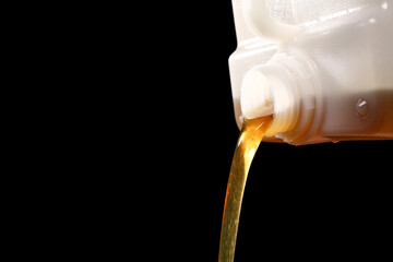 Pouring of machine oil from canister on black background, closeup
