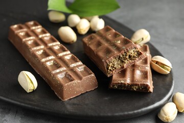 Delicious Dubai chocolate bars and pistachios on grey table, closeup