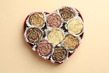 Flower shaped chocolate bonbons in box on beige background, top view