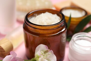 Body care products, flowers and leaves on pink background, closeup