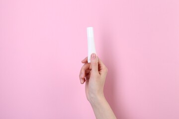 Woman with tube of cream on pink background, closeup. Body care product