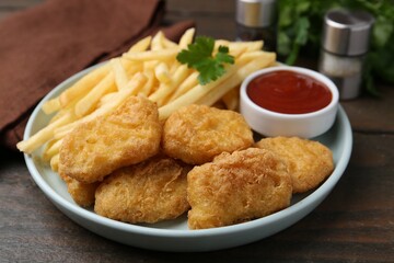Tasty chicken nuggets and french fries with sauce on wooden table, closeup