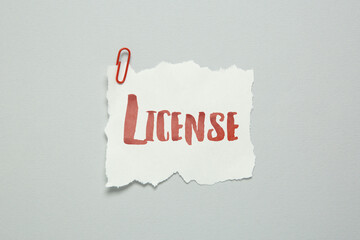 Piece of paper with word License and paperclip on white background, top view