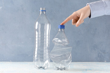 Female hand with plastic bottles on color background
