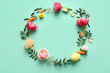 Frame made of Easter eggs, flowers, green leaves and decor on turquoise background