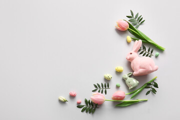 Frame made of Easter eggs, green leaves, tulip flowers and decor on grey background