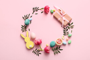 Frame made of Easter eggs, gift box, flowers, green leaves and decor on pink background