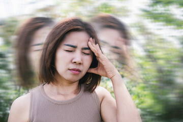 Asian woman suffering from anemia, experiencing syncope, dizziness, and vertigo while walking outdoor due to reduced oxygen levels