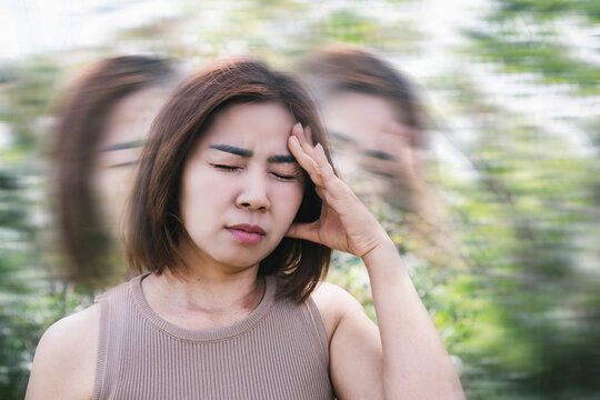 Asian woman suffering from anemia, experiencing syncope, dizziness, and vertigo while walking outdoor due to reduced oxygen levels