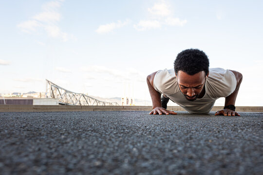 Determined male athlete doing push-ups outdoors in urban setting
