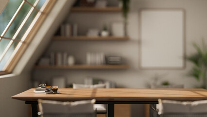 A wooden table with books and coffee under large window, with the blurred background of sunlit room.