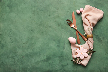 Stylish cutlery with sweet cookie, Easter eggs and gypsophila flowers on green background