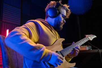 Man vocal artist singing in a recording studio with guitar. Male singer singing a song and playing...