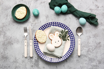 Beautiful table setting with sweet cookies, Easter eggs and leaves on grey background
