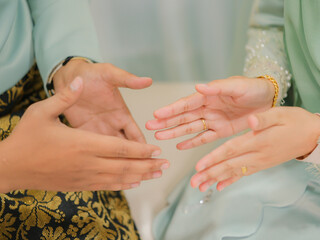 The groom put the wedding bracelet to the bride during solemnization ceremony. Family and happiness concept.