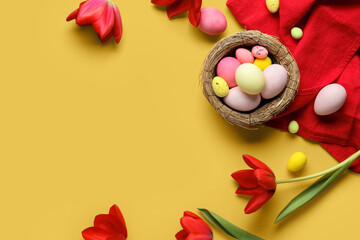 Easter eggs, decorative nest, napkin and tulip flowers on yellow background