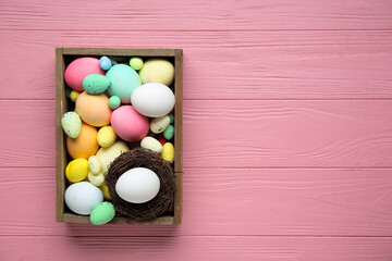 Box with different Easter eggs on pink wooden background