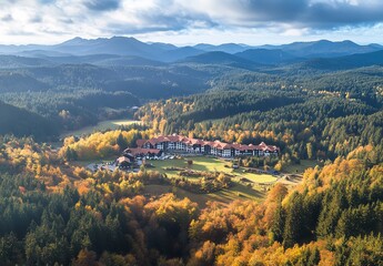 Naklejka premium A Wide View of a Forested Valley with Trees Displaying Hints of Autumn Colors, Under a Dramatic Overcast Sky with Low-Hanging Clouds.