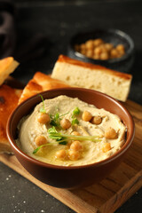 Bowl of delicious hummus with micro green and chickpeas on grunge grey background