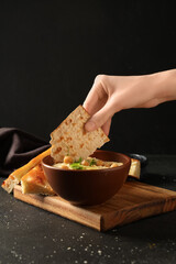 Woman eating delicious hummus with chickpeas, micro green and crispbread on grey grunge background