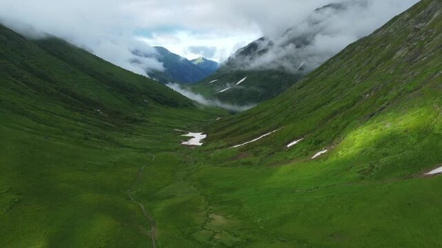 Airial green valley between the mountains. Cloudy summer
