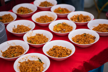 Fried noodles prepared in white bowls serving at the buffet.