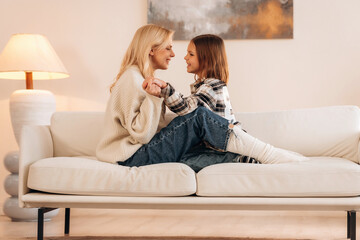 Calm and cute. Sitting on the sofa. Mother and daughter are together in domestic room