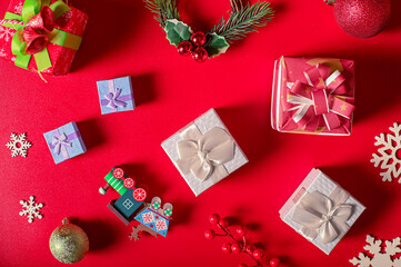 A festive Boxing Day preparation flat lay with Christmas decorations: gift boxes, candy cane, ornaments, and greenery on a vibrant red background, creating a cheerful holiday atmosphere