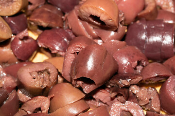 Close up of roughly chopped slice Kalamata Olives on Wooden Chopping Board