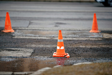 Orange traffic cones. Asphalt pavement restoration site with traffic cones marking the repaired...