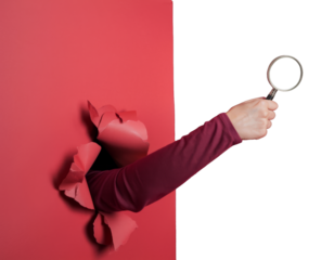 magnifying glass held by hand through torn red paper background