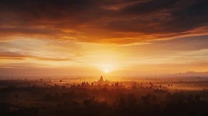 Obraz premium A beautiful sunset view in orange and yellow, with a small structure of a Khmer temple in the middle, surrounded by forest.