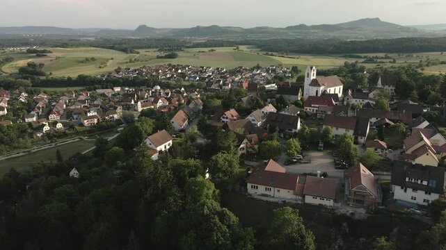 Drone footage orbits leftwards around Aach village from a fresh angle, offering a unique view of the church tower, old town, and surrounding landscape.