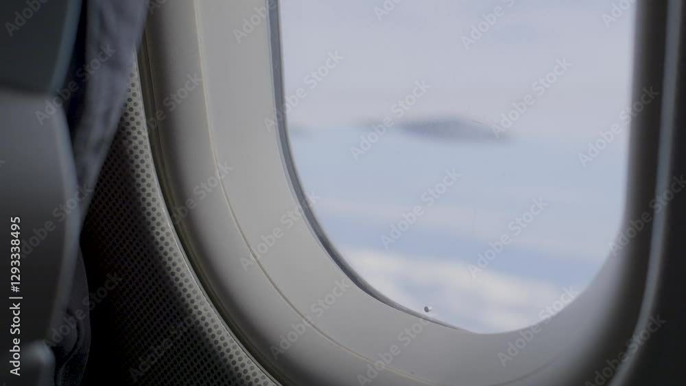 Poster looking out of an airplane window with a cloudy sky in the background