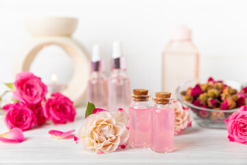 Rose essential oil on a textured background.Roses and a bottle of rose perfumed water.Aromatherapy treatment. Beauty concept. Spa procedure.Natural organic oil.Anti-stress,detox relax.Place for text