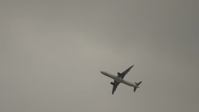 SLOW MOTION: TRACKING SHOT OF AN A321 PLANE FLYING OVER AT A CLOUDY DAY
