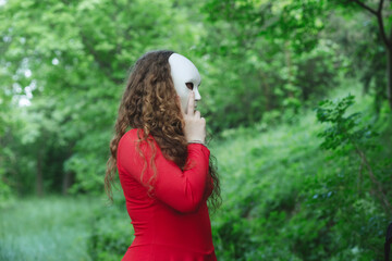 mysterious woman with mask wanders in the middle of a green forest