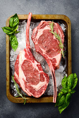 Raw uncooked black angus beef tomahawk steaks laid out on ice. Close up. Top view.
