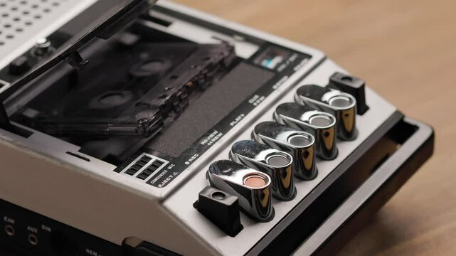 Person pressing eject button on vintage cassette recorder