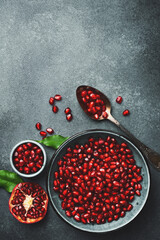 Ripe pomegranate grains, and pomegranate seeds in a bowl. On a concrete background. Top view.