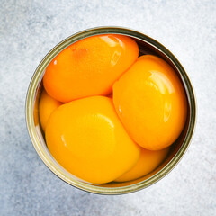 Pickled peaches in a metal jar. Food stocks. On a gray concrete background.