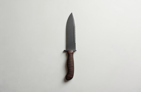 Isolate photo of black military combat knife. Sharp steel blade, brown handle. Modern commando equipment, hunting tool. Stainless metal edge. War, fight, self-defense conceptual shot for background,