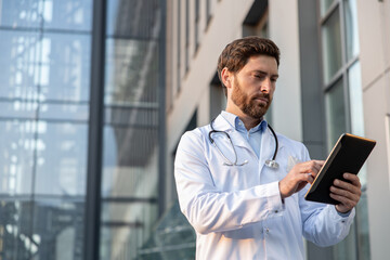 Ginger man in a lab coat with a tablet in hands looking determined