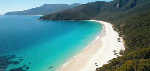 Aerial view of Wineglass Bay. Turquoise waters meet white sand beach in Freycinet National Park, Tasmania, Australia. Mountain range and rich green forest surround paradise lagoon coastline.