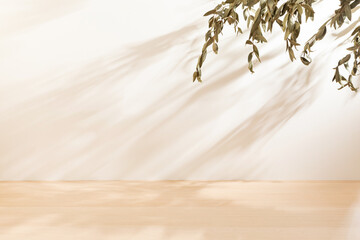 Horizontal blank warm lighting background. Blank wallpaper with leaf foreground. White and Wooden surface. Light and Shadow wallpaper. Space for text. Backdrop. Studio photography. Sunshine. Elegant.
