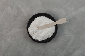 Sodium percarbonate powder SPC or sodium carbonate peroxide in black dish with ceramic spatula....