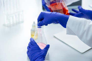 Specialist in sterile lab working with chemical substances examining solutions in transparent flask
